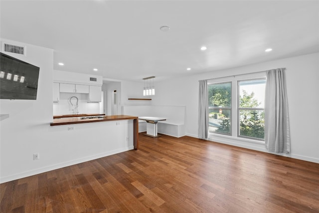 kitchen featuring wood counters, sink, pendant lighting, wood-type flooring, and white cabinetry