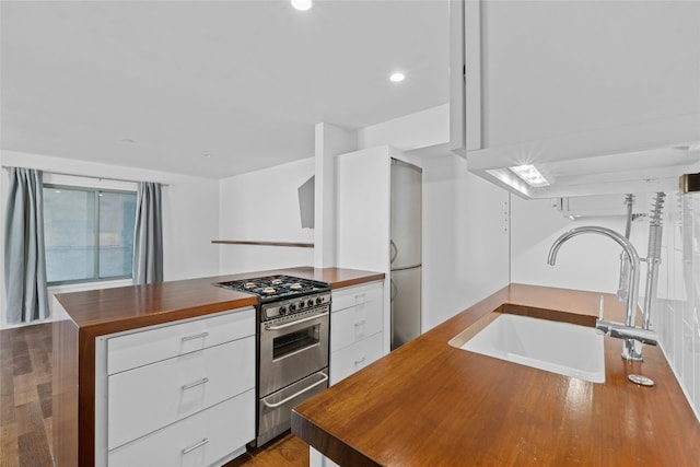 kitchen featuring gas range, a center island, sink, hardwood / wood-style floors, and white cabinets