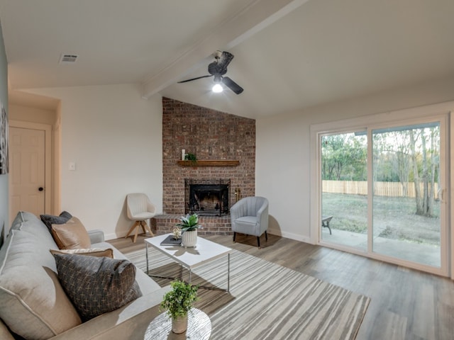 living room with vaulted ceiling with beams, ceiling fan, light wood-type flooring, and a fireplace