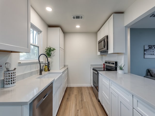 kitchen featuring white cabinetry, light wood-type flooring, and appliances with stainless steel finishes