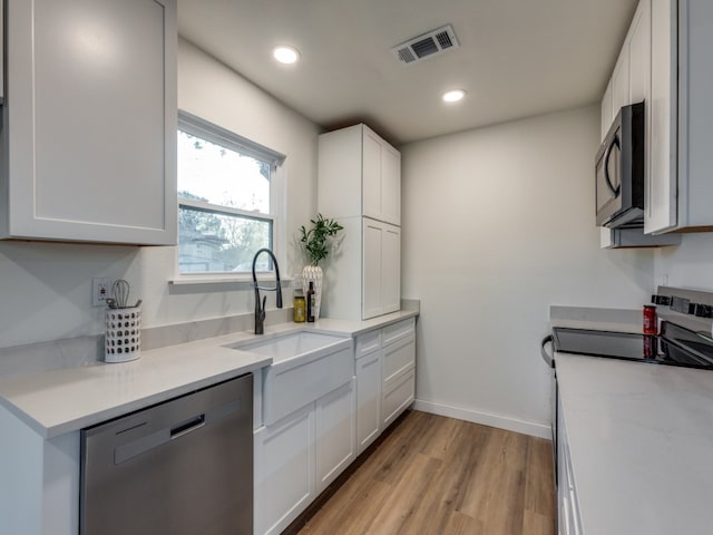 kitchen featuring white cabinets, light hardwood / wood-style floors, sink, and appliances with stainless steel finishes