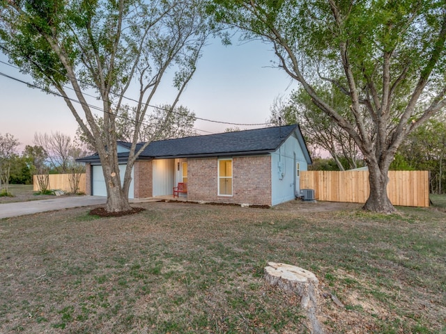 ranch-style home with a garage, central AC unit, and a lawn