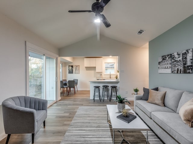 living room featuring light hardwood / wood-style floors, vaulted ceiling, ceiling fan, and sink