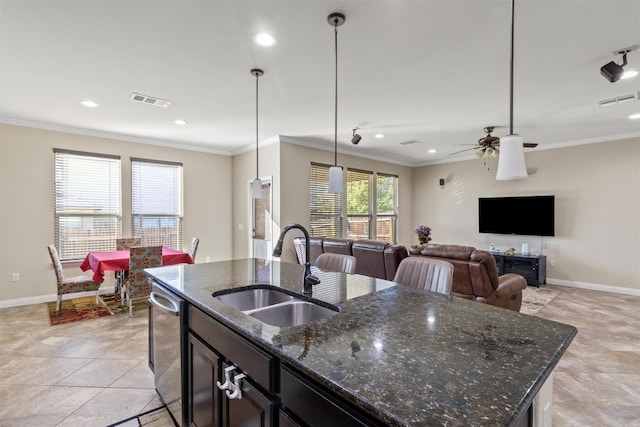 kitchen featuring dark stone counters, ceiling fan, a kitchen island with sink, sink, and hanging light fixtures