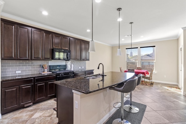 kitchen featuring sink, decorative light fixtures, a breakfast bar area, a center island with sink, and black appliances