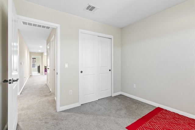 unfurnished bedroom with light carpet and a closet