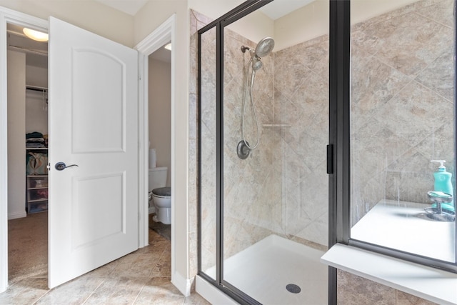 bathroom featuring tile patterned floors, a shower with shower door, and toilet