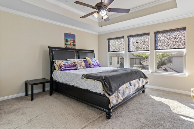 carpeted bedroom with ceiling fan, ornamental molding, and a tray ceiling