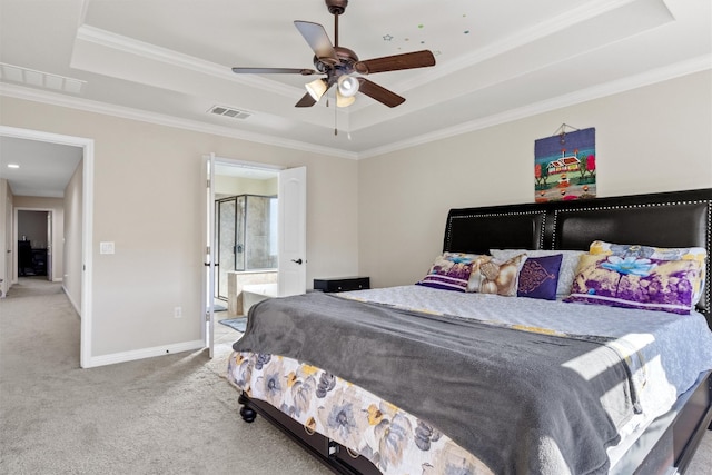 carpeted bedroom featuring a tray ceiling, ensuite bathroom, crown molding, and ceiling fan