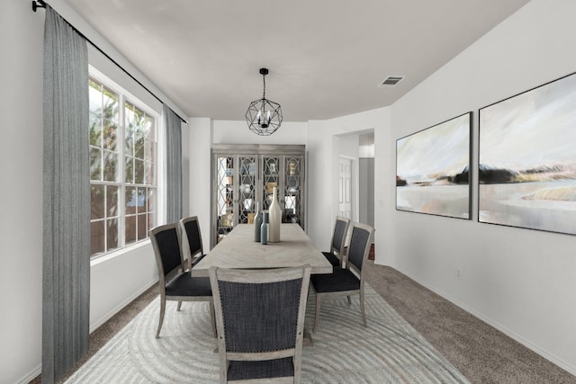 carpeted dining area with an inviting chandelier