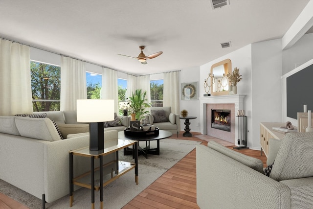 living room featuring a tiled fireplace, hardwood / wood-style floors, and ceiling fan