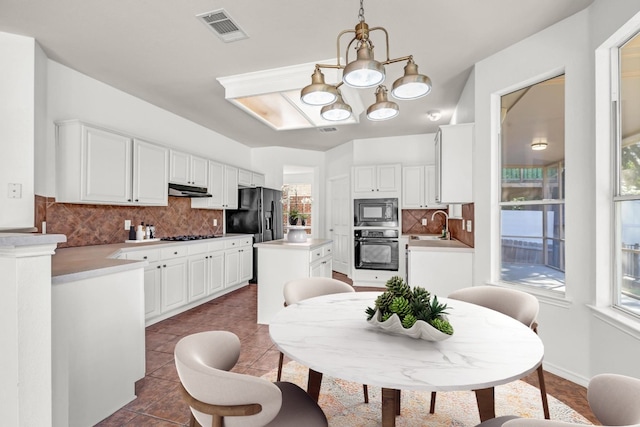 kitchen featuring pendant lighting, white cabinets, an inviting chandelier, and black appliances