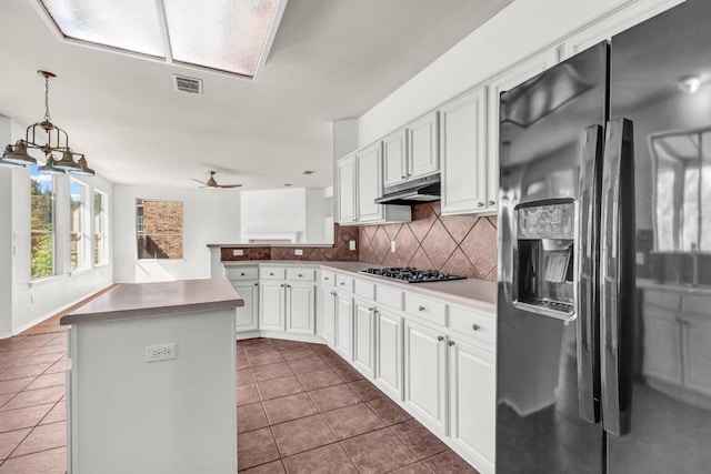 kitchen with black refrigerator with ice dispenser, hanging light fixtures, kitchen peninsula, dark tile patterned floors, and white cabinets