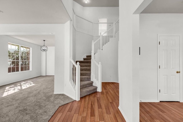 stairway with wood-type flooring and a notable chandelier