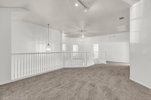 carpeted spare room with vaulted ceiling and track lighting