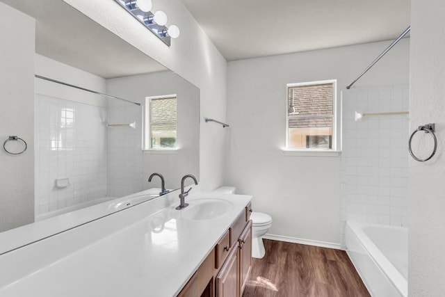 full bathroom with hardwood / wood-style flooring, vanity, tiled shower / bath, and toilet