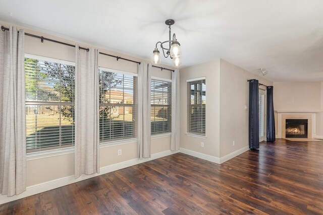 unfurnished dining area with dark hardwood / wood-style flooring, an inviting chandelier, and a healthy amount of sunlight