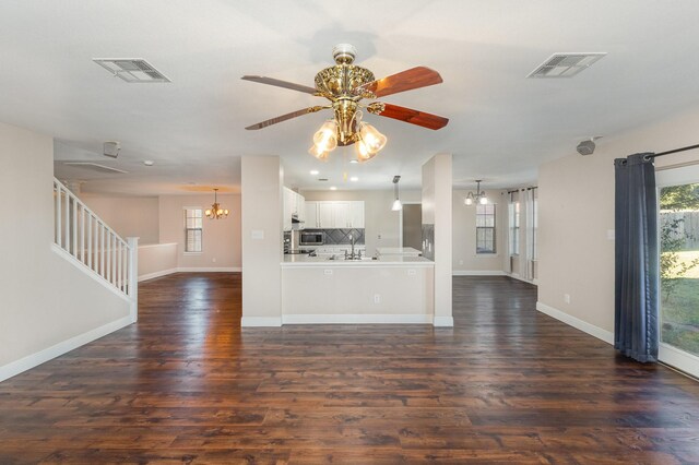 unfurnished living room featuring dark hardwood / wood-style flooring and ceiling fan with notable chandelier