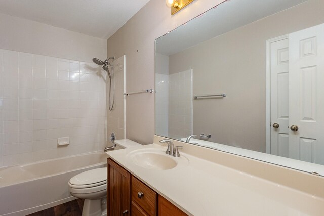 full bathroom with hardwood / wood-style flooring, vanity, tiled shower / bath combo, and toilet