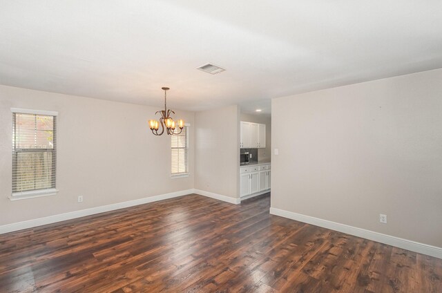 unfurnished room featuring an inviting chandelier and dark wood-type flooring