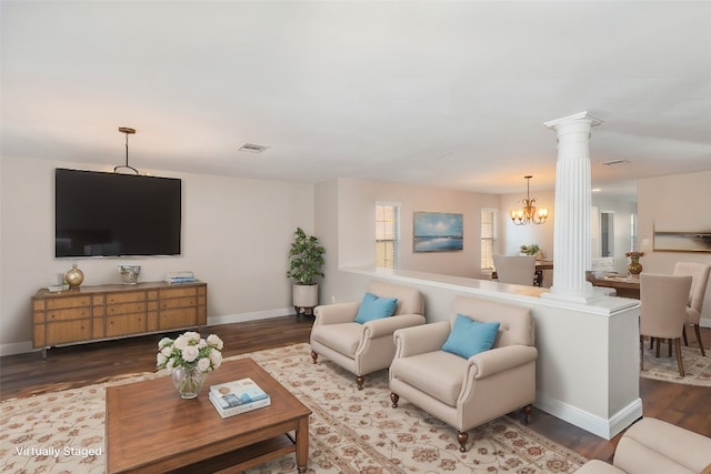 living room featuring wood-type flooring, ornate columns, and a notable chandelier