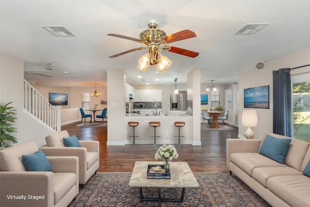 living room featuring sink, dark hardwood / wood-style floors, and ceiling fan with notable chandelier