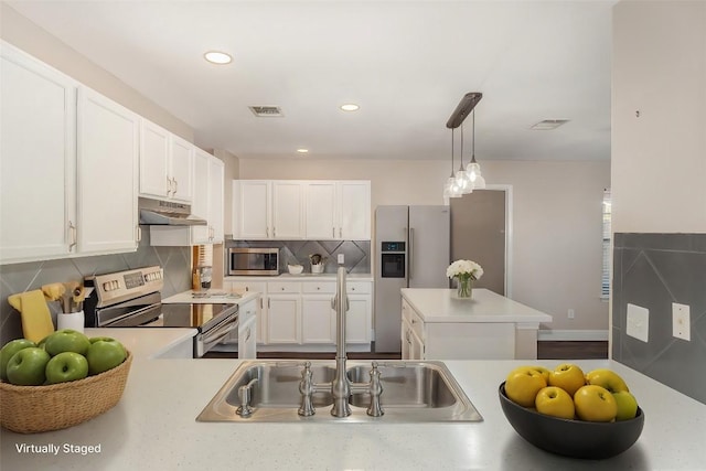 kitchen with tasteful backsplash, white cabinetry, appliances with stainless steel finishes, and pendant lighting