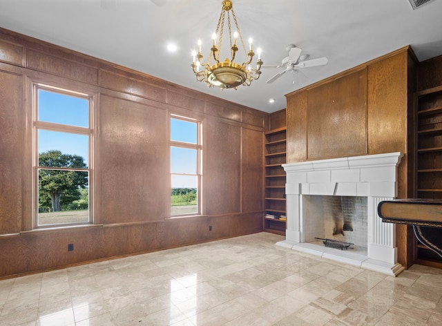 unfurnished living room featuring wood walls, built in shelves, and a healthy amount of sunlight