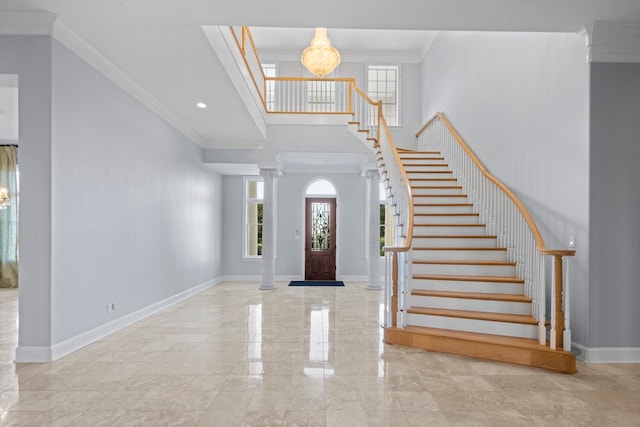 entrance foyer featuring decorative columns, an inviting chandelier, and ornamental molding