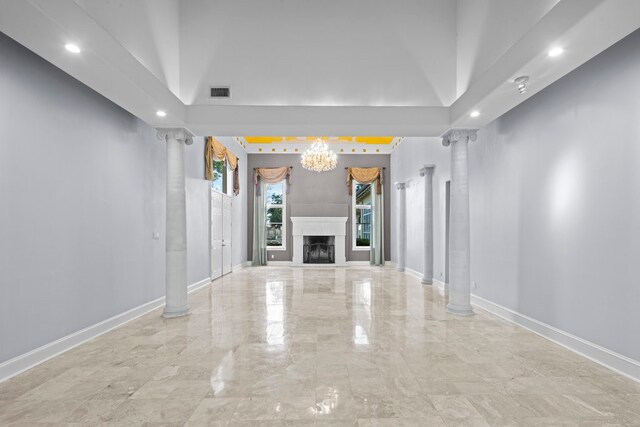 unfurnished living room featuring decorative columns, high vaulted ceiling, and a chandelier