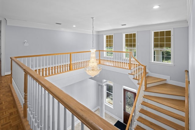 corridor with dark parquet flooring, crown molding, and a notable chandelier