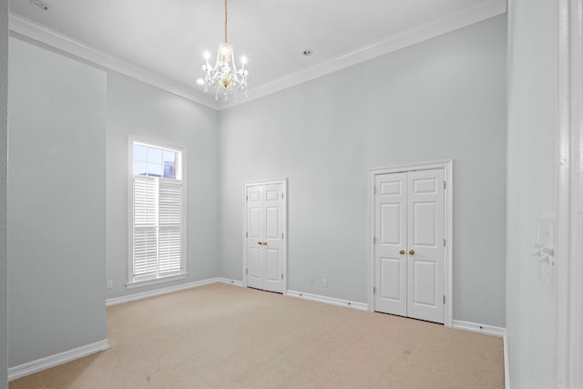 carpeted spare room with a towering ceiling, an inviting chandelier, and ornamental molding