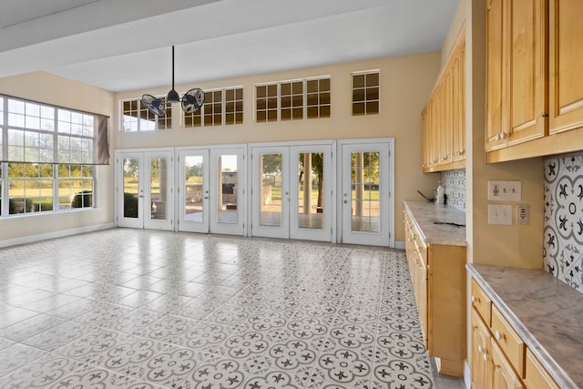 interior space with pendant lighting, plenty of natural light, light brown cabinets, and an inviting chandelier