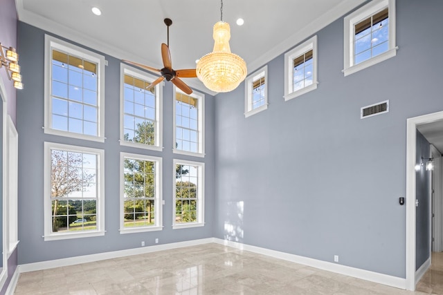 spare room with a towering ceiling, crown molding, and an inviting chandelier