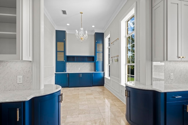 kitchen with an inviting chandelier, crown molding, hanging light fixtures, light stone countertops, and blue cabinetry