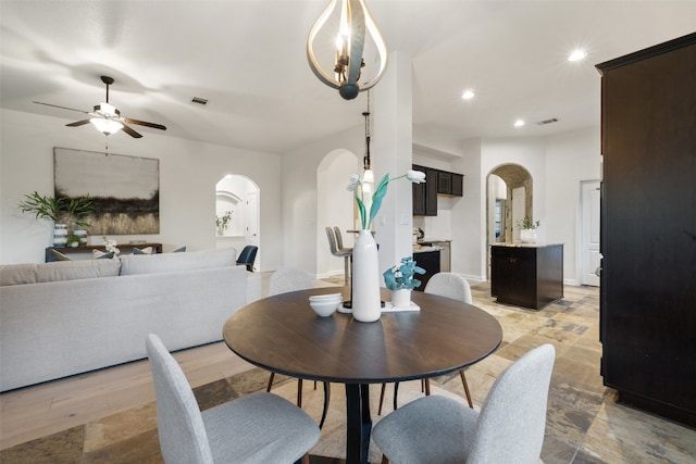 dining room featuring ceiling fan with notable chandelier and light hardwood / wood-style flooring