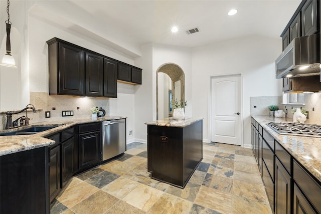 kitchen featuring sink, hanging light fixtures, decorative backsplash, appliances with stainless steel finishes, and light stone counters