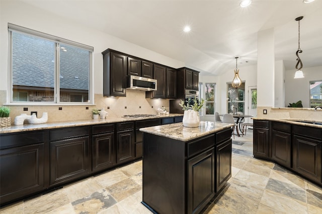 kitchen with lofted ceiling, sink, appliances with stainless steel finishes, tasteful backsplash, and decorative light fixtures