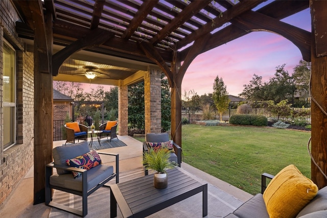 patio terrace at dusk featuring a pergola, ceiling fan, a lawn, and an outdoor living space