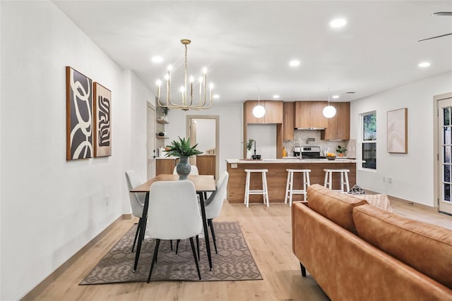 dining space with light hardwood / wood-style floors and an inviting chandelier