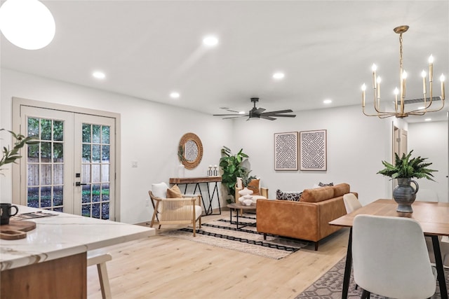 living room featuring ceiling fan with notable chandelier, light wood-type flooring, and french doors