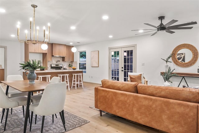 dining room featuring ceiling fan with notable chandelier, light hardwood / wood-style floors, sink, and french doors