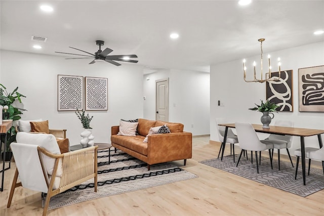 living room featuring light hardwood / wood-style flooring and ceiling fan with notable chandelier