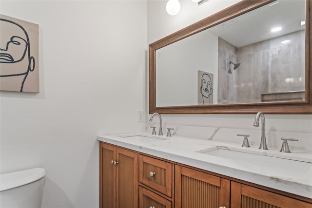 bathroom with a tile shower, vanity, and toilet