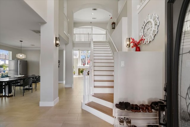 tiled foyer entrance featuring a high ceiling and ornamental molding