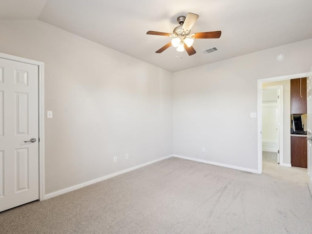 spare room featuring light carpet, lofted ceiling, and ceiling fan