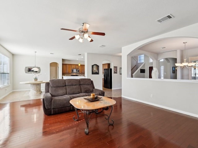 living room with ceiling fan with notable chandelier and light hardwood / wood-style flooring