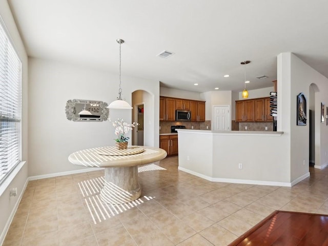 kitchen with pendant lighting, plenty of natural light, light tile patterned floors, and backsplash