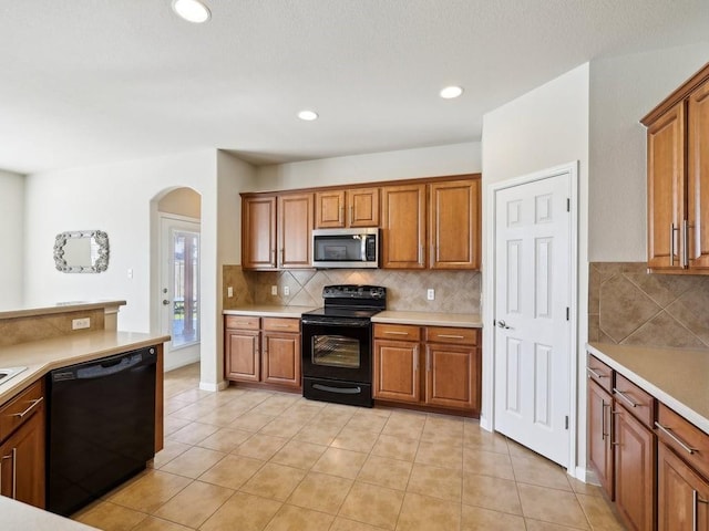 kitchen featuring decorative backsplash, light tile patterned floors, and black appliances