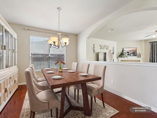 dining room featuring ceiling fan with notable chandelier and dark hardwood / wood-style flooring